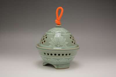 This garlic keeper was hand-thrown and hand-carved with traditional Asian patterns.  The patterns include water lilies and lotus flowers (not shown).  This is not a traditional garlic keeper but its design is perfect for garlic considering its wide opening for taking garlic out and enough holes for air circulation.  And it can hold 3 to 4 garlic bulbs.  By removing the rope from the lid, it can also function as an incense burner.  Rope for the handle is not included.