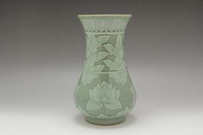 This vase was hand-thrown on a pottery wheel and hand-carved with lotus flowers accompanied with peony leaves along its neck.  