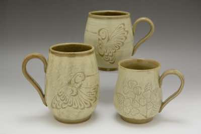 These coffee mugs were hand-thrown, brushed on white-colored slip with hand-made straw brush and, on top of the slip, hand-carved with patterns of birds and flowers which can be found in Canada.  The patterns include hummingbirds, dogwood flowers and cherry blossoms (not shown).  They come in 3 sizes - small (400ml or 13.5oz), medium (550ml or 18.5oz) and large (700ml or 23.5oz).    