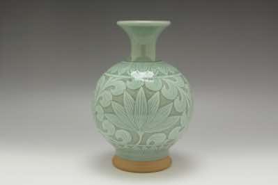 This vase was hand-thrown on a pottery wheel and hand-carved with water lilies.  The footing was deliberately unglazed to show the color and smoothness of the clay used in this vessel.